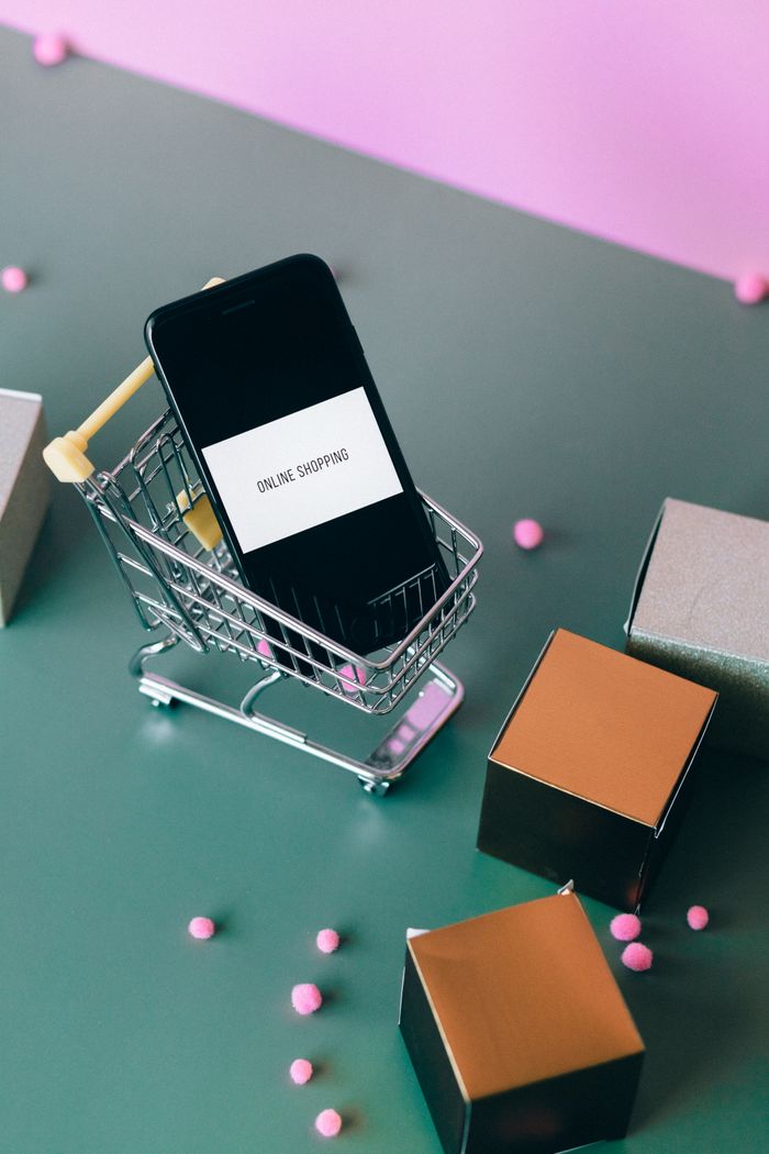 about-us-01 Conceptual image of online shopping with a smartphone in a miniature cart.