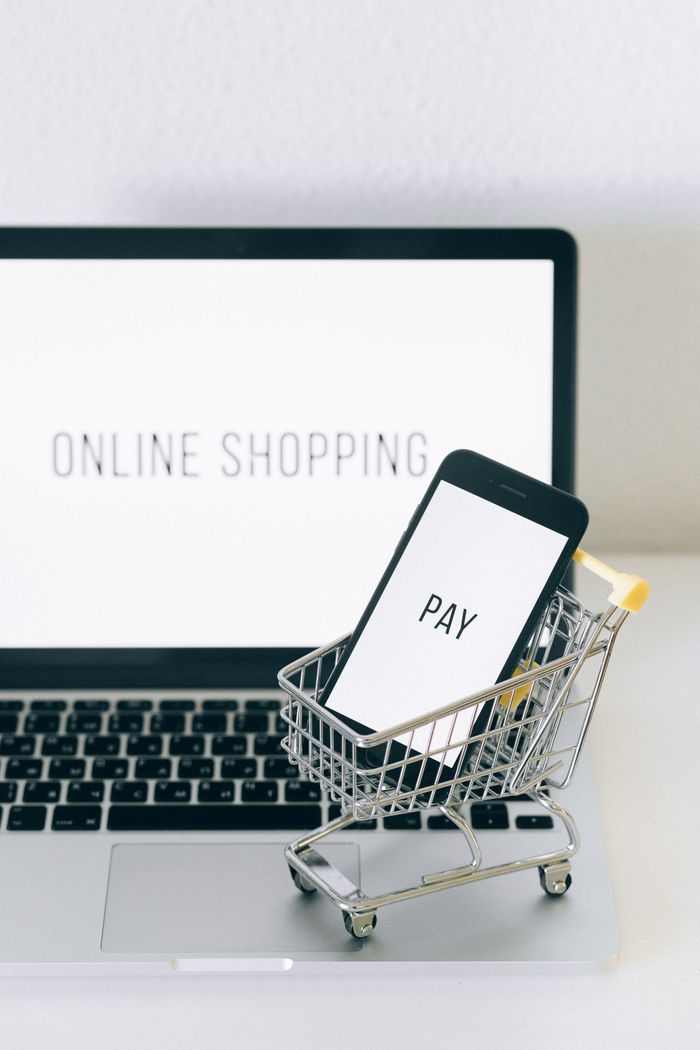 about-us-02 A smartphone in a miniature cart on a laptop symbolizes online shopping and digital payment.